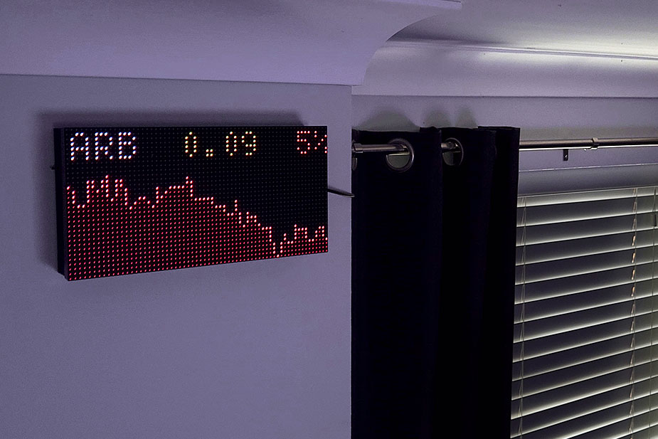 A red market chart on a wall-mounted ticker